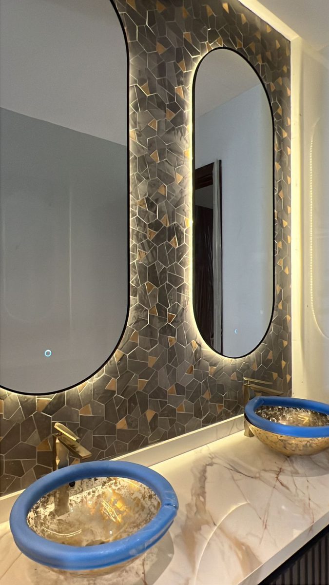 Fluted timber vanity with artisanal gold-leaf glass vessel sink and geometric wall mosaic