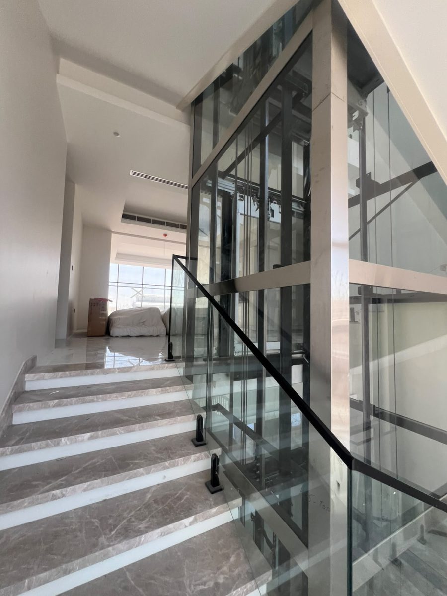 Floating marble staircase with frameless glass balustrade and backlit Patagonia quartzite wall