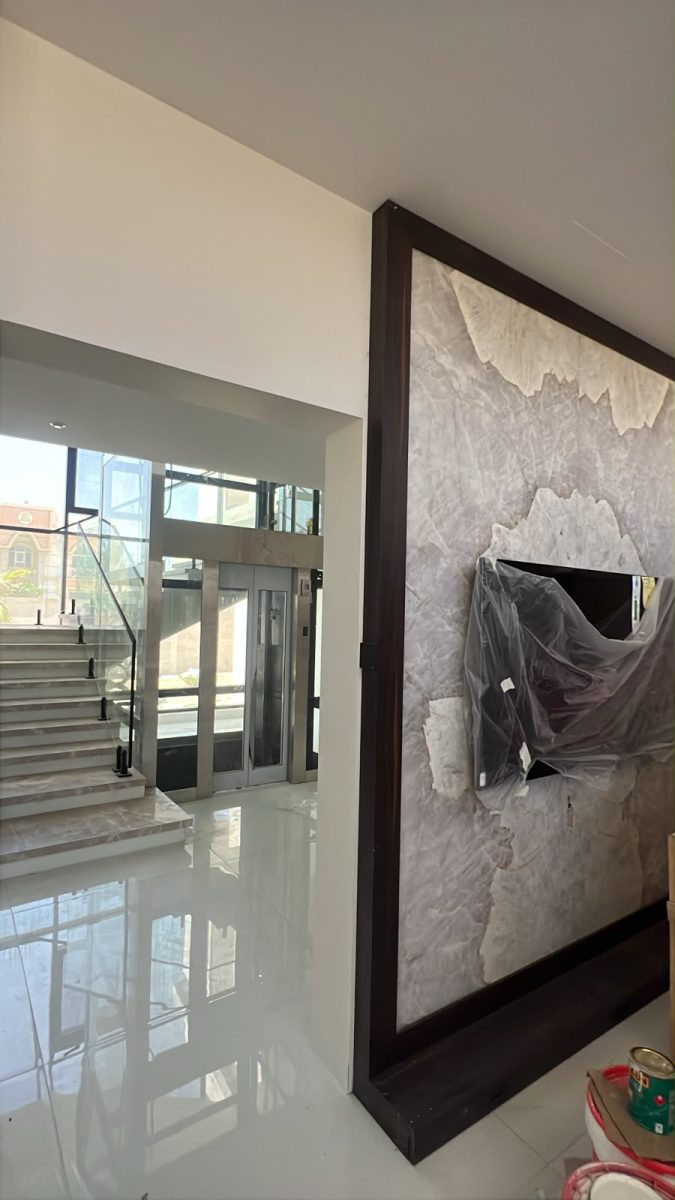 Panoramic glass hydraulic elevator in central light atrium with marble floating staircase